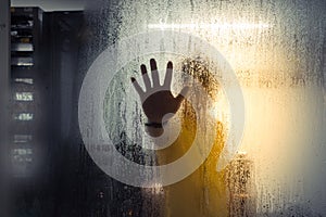 Silhouette of man on glass with drop in computer server room