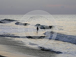 silhouette of a man go to the ocean, facing the waves
