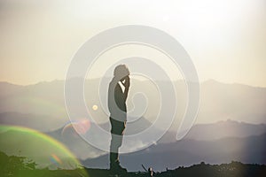 Silhouette of a man with hands raised in the sunset