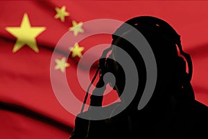 Silhouette of a man in headphones, secret agent eavesdropping, spy and scout, China flag, backlight