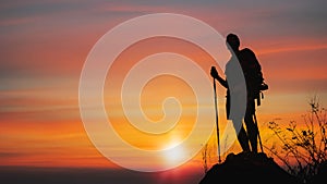 Silhouette of man hiker standing on rocky mountain peak with sunset golden sky feeling of freedom