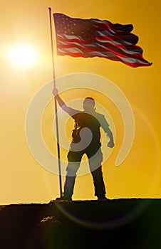 Silhouette of man holding US flag American on the mountain.