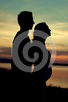 Silhouette of the man hugging his pregnant wife