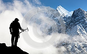 Silhouette of man with ice axe in hand and mountains