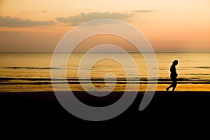 Silhouette of a man jogging on the beach at sunset, healthy lifestyle