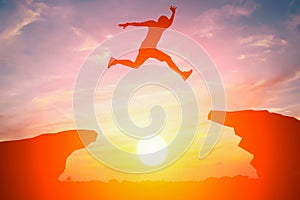 Silhouette of man jump over the cliff