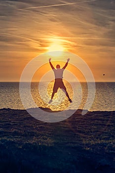 Silhouette of a man jumping on a beach during sunrise