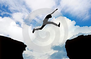 Silhouette of man jumping cliff