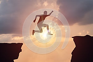 Silhouette of man jumping over a gap at sunset