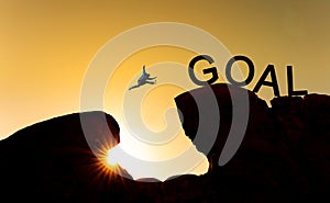 Silhouette a man jumping over precipice to goal. Achieve goal, business goals, challenge and success concept photo