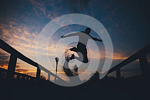 Silhouette of a man jumping in sand at sunset