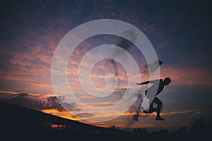 Silhouette of a man jumping in sand at sunset