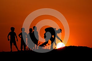 Silhouette of man with the kids touching Sun, Maharashtra, India