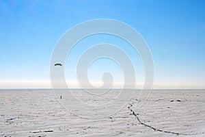 Silhouette of a man kiting in winter time at frozen lake