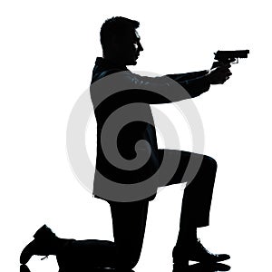 Silhouette man kneeling aiming gun photo