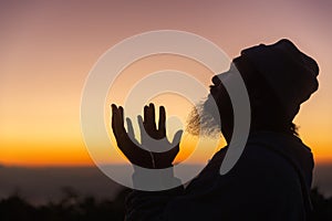 Silhouette of man kneeling down praying for worship God at sky background. Christians pray to jesus christ for calmness. In