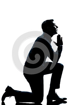 Silhouette man kneeling praying full length