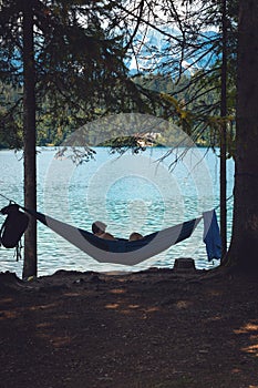Silhouette of a man lie in the hammock near the lake. Calm, around the forest, silhouettes of trees, pine. Bled, Slovenia.
