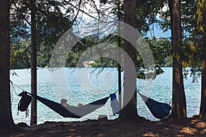 Silhouette of a man lie in the hammock near the lake. Calm, around the forest, silhouettes of trees, pine. Bled, Slovenia