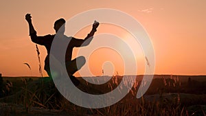 Silhouette of a man in a lotus position. A man meditates at sunset on the top of a mountain. Do yoga in nature
