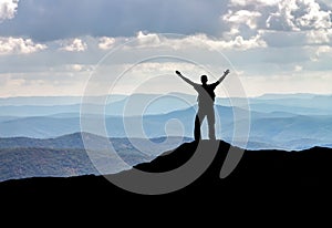 Silhouette of a man on a mountain top.