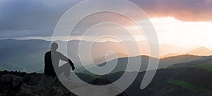 Silhouette of Man on a mountain top Sunset Background