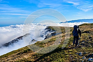 Silhouette of a man in the mountains. Successfully achieving goals. Male hiker on mountain peak with green grass looking