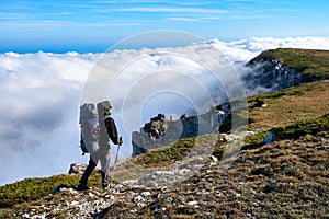 Silhouette of a man in the mountains. Successfully achieving goals. Male hiker on mountain peak with green grass looking