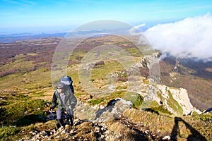 Silhouette of a man in the mountains. Successfully achieving goals. Male hiker on mountain peak with green grass looking