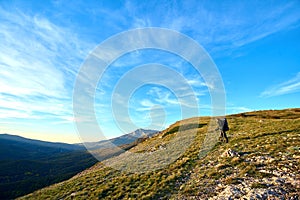 Silhouette of a man in the mountains. Successfully achieving goals. Male hiker on mountain peak with green grass looking