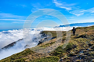 Silhouette of a man in the mountains. Successfully achieving goals. Male hiker on mountain peak with green grass looking