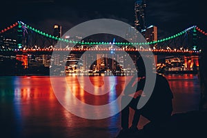 Silhouette of man near river in night city