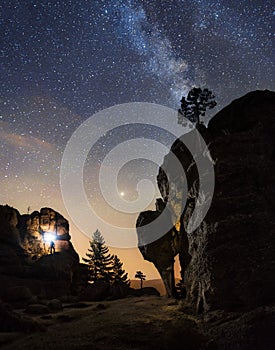 Silhouette of a man  in the night on top of the mountain with a torch under an amazing the milky way