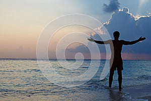 Silhouette Of Man With Outstretched Arms On Beach