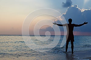 Silhouette Of Man With Outstretched Arms On Beach photo