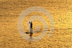 Silhouette of man paddleboarding photo