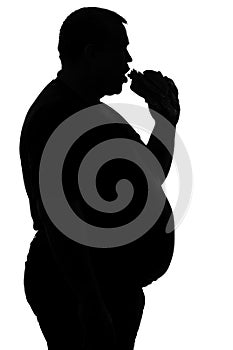 Silhouette of a man paunchy eating fast food -