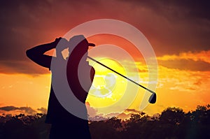 Silhouette of man playing golf at sunset