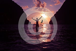 Silhouette of a man playing with sea water and the big fish jumping by the beach at sunrise