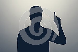 silhouette of man pointing up with his finger isolated on gray background.