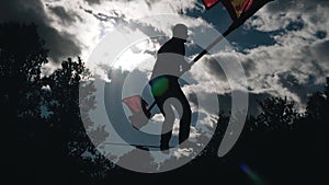 The silhouette of a man with a pole jumping on a rope above the ground.