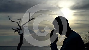 Silhouette of Man pray on sunset and dramatic sky background. Repentance, regret and hope concept