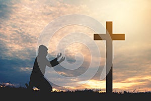 Silhouette man praying with cross