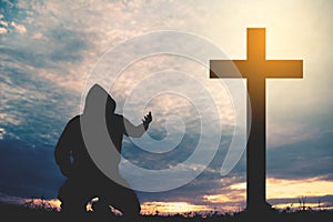 Silhouette man praying with cross