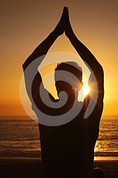 Silhouette, man and praying with hands for yoga, health and wellness on beach with sunset and zen. Person, shadow and