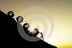 Silhouette of man pushing a debt rock that rolls down a mountain for resist debt and financial freedom concept