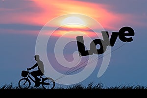 Silhouette of man ride on bicycle with air balloons for wording LOVE at sunset sky (Love valentine concept)