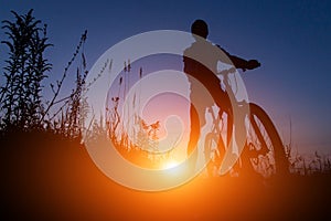 Silhouette of man riding bicycle in sunset sky background