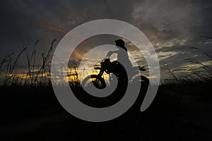 Silhouette of a man riding his motorcycle during sunset.