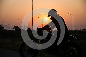 Silhouette of man riding vintage motorcycle cafe racer style with helmet